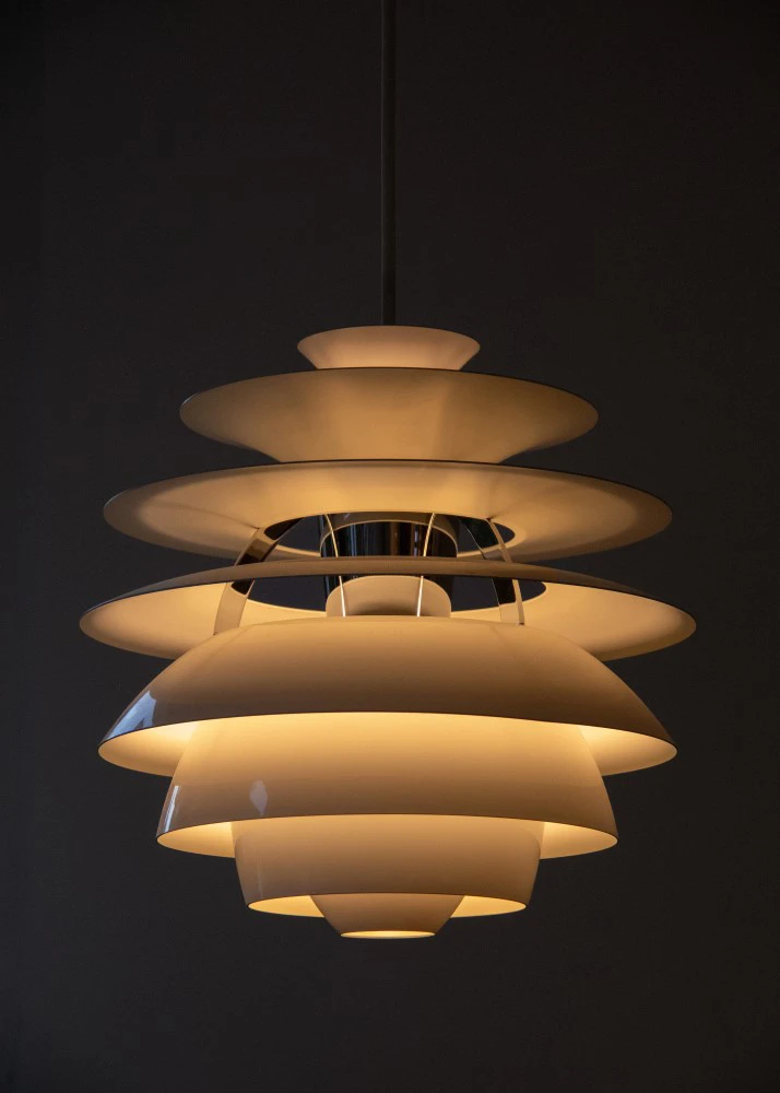 A white PH Snowball pendant glows warmly against a dark background. © 2026 Louis Poulsen.