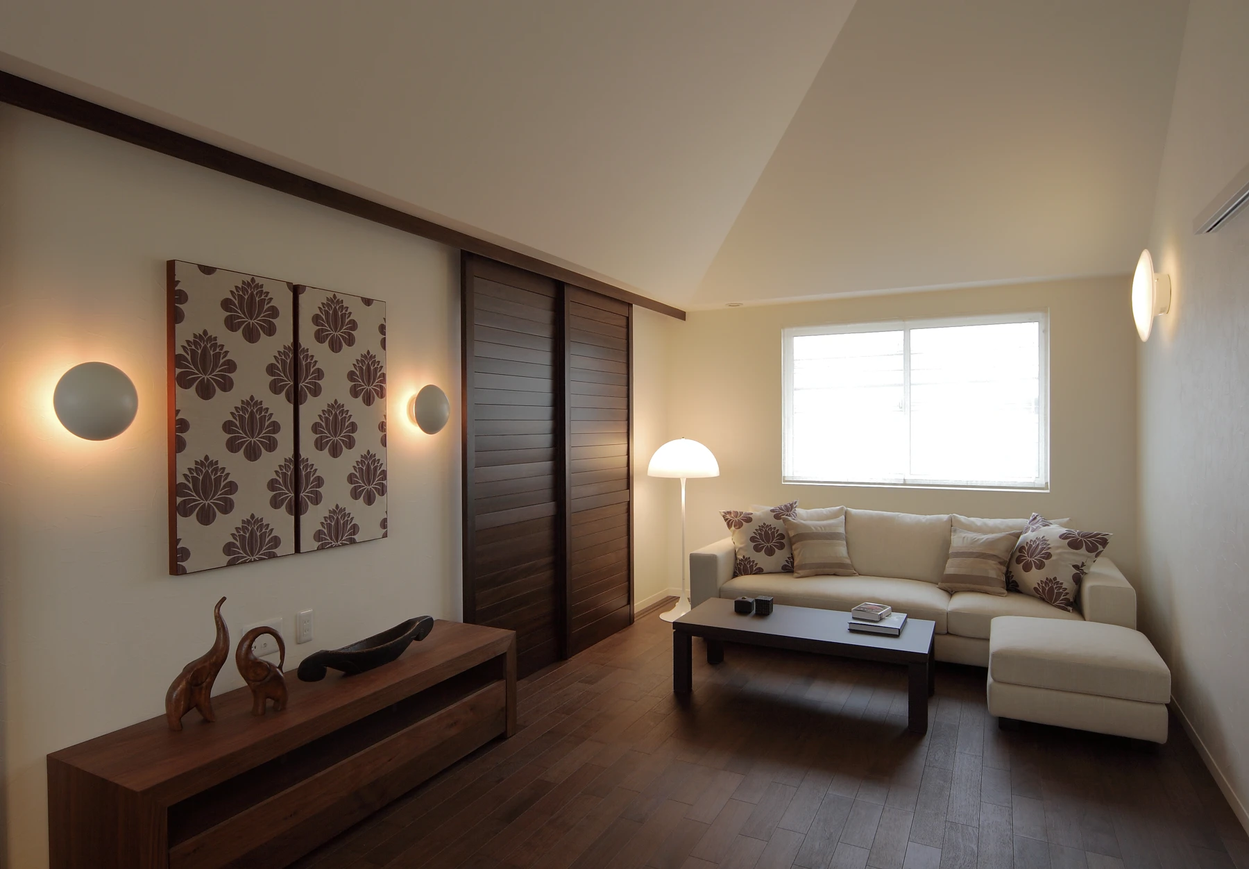 A Panthella Floor Lamp and Flindt Wall Lamps illuminate a living room with dark wood floors and a light sofa. © 2026 Louis Poulsen.