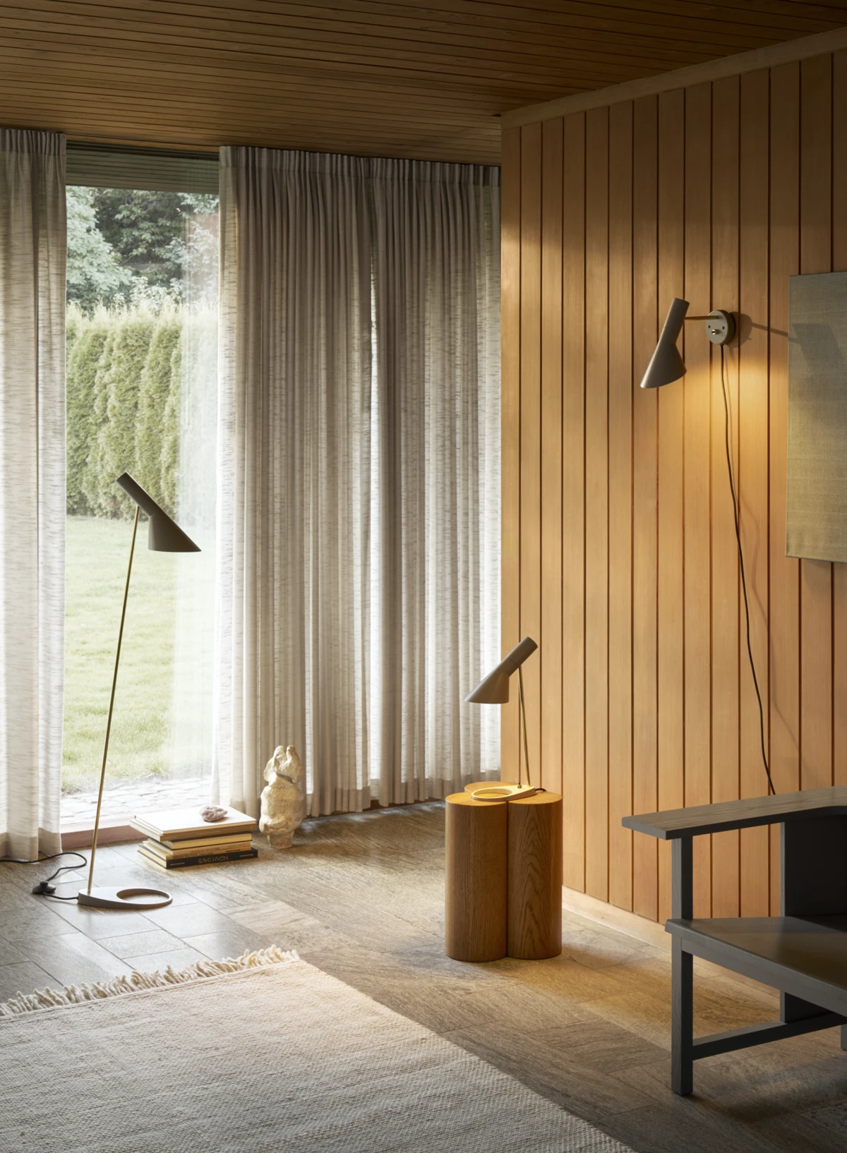 Arne Jacobsen floor lamp, table lamp, and wall lamp, all with brass detailing on the stems, © 2025 Louis Poulsen.