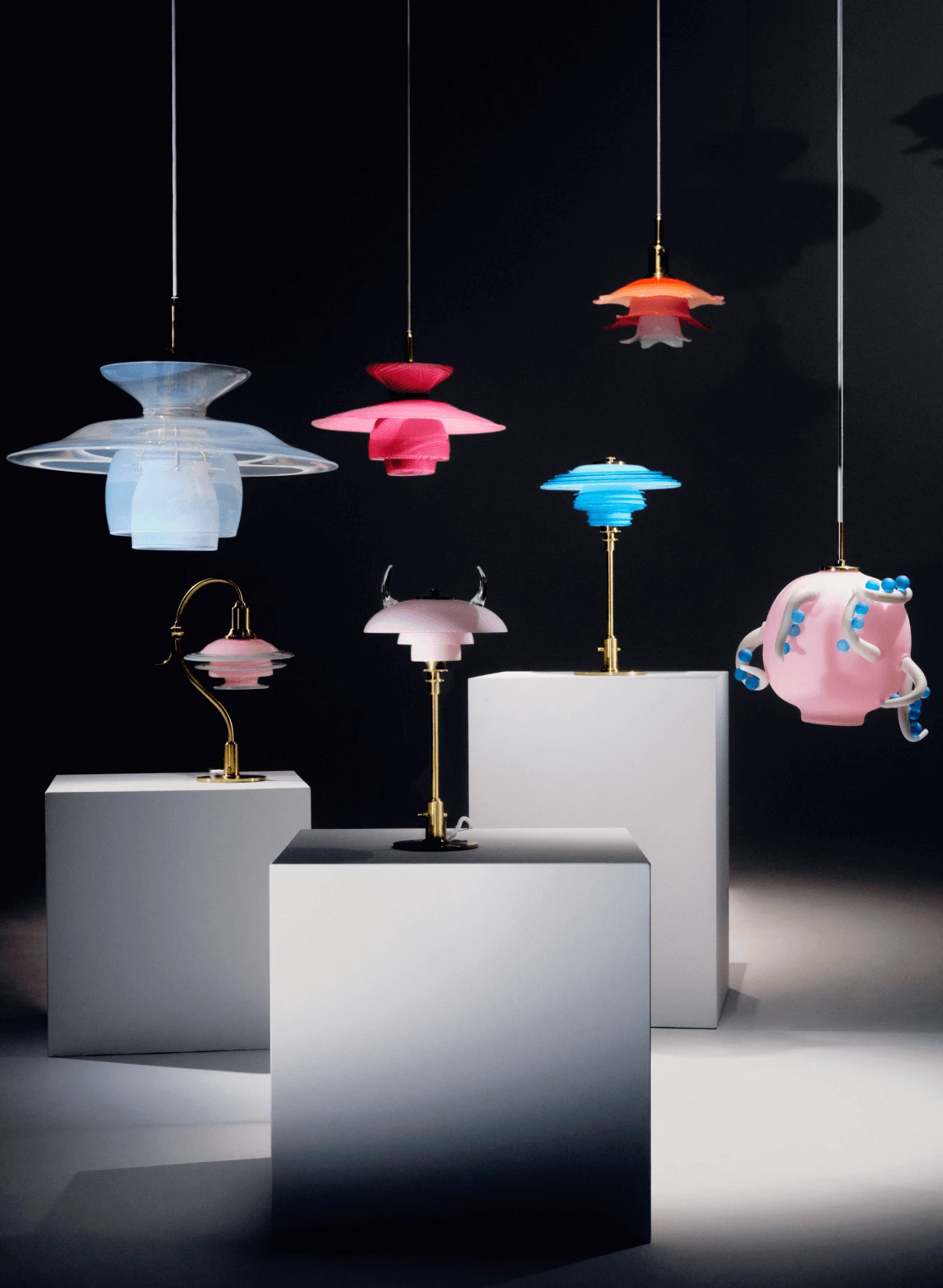 Colorful lamps in playful reinterpretations displayed on white plinths, © 2025 Louis Poulsen.