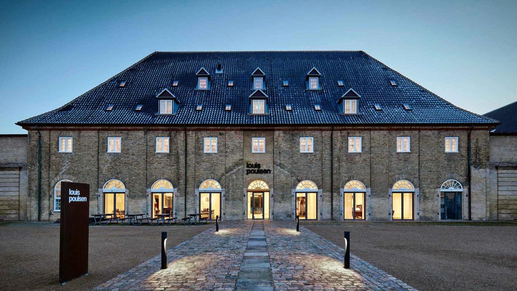 Louis Poulsen showroom building at dusk with pathway lit by Flindt Bollard lamps, © 2025 Louis Poulsen.