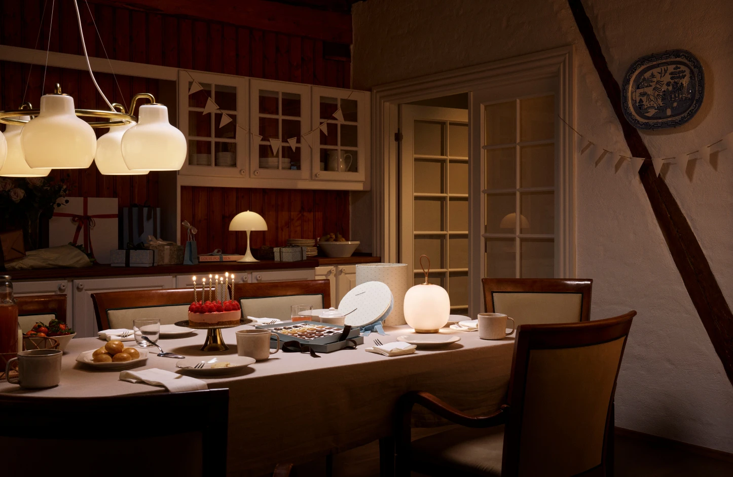 A white PH 5 pendant and Panthella 250 Table Lamp light a set dining table in a warm, rustic kitchen. © 2026 Louis Poulsen.