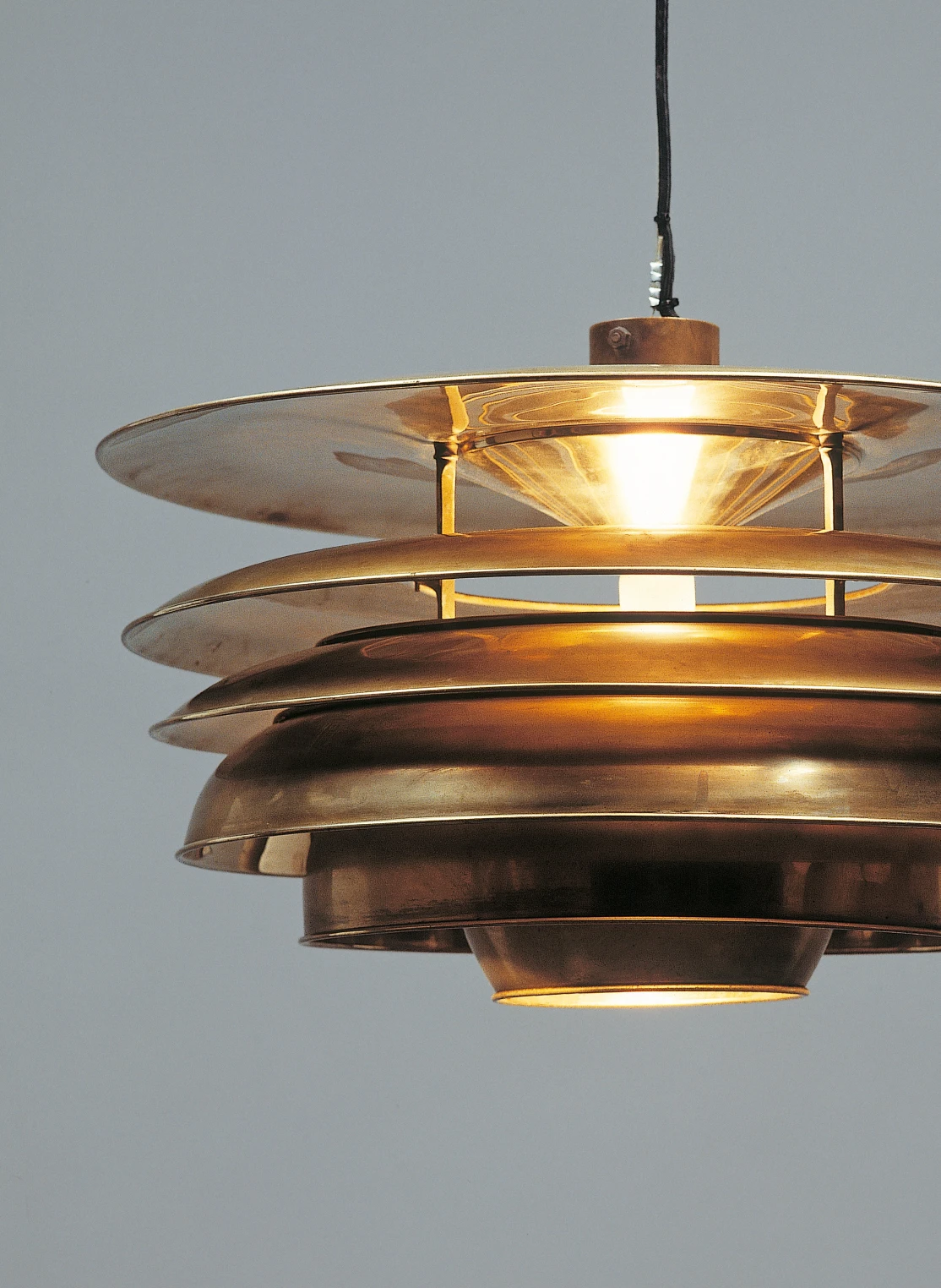 PH 5-4½ & PH 6½-6 pendel i varm metallfinish lyser mot en grå bakgrund. © 2026 Louis Poulsen.