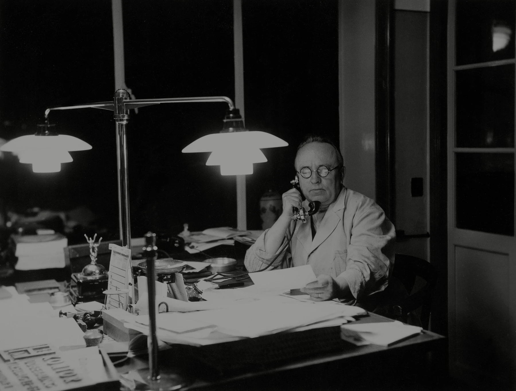 Poul Henningsen working at desk with PH vintage table lamp, © 2025 Louis Poulsen.