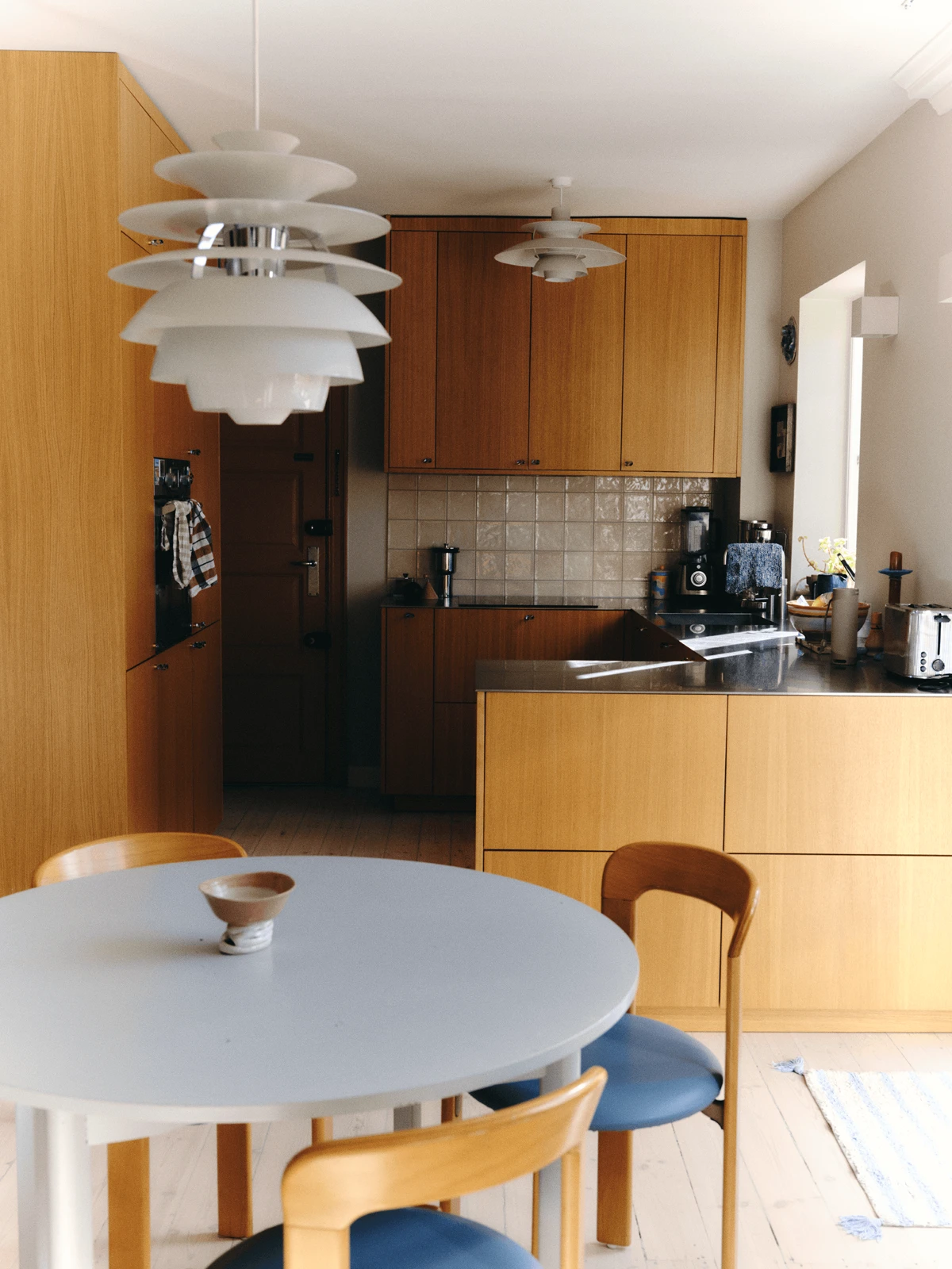 PH pendants hanging above dining table connecting kitchen and dining space, © 2025 Louis Poulsen.