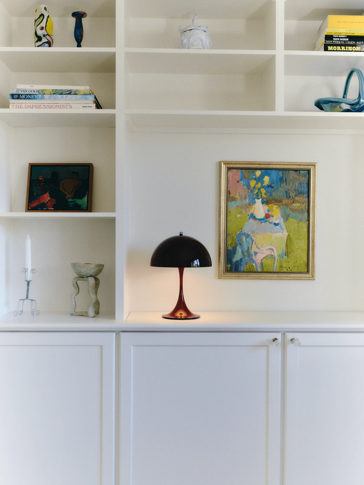 Panthella Table Lamp displayed on built-in shelves among art and ceramics, © 2025 Louis Poulsen.