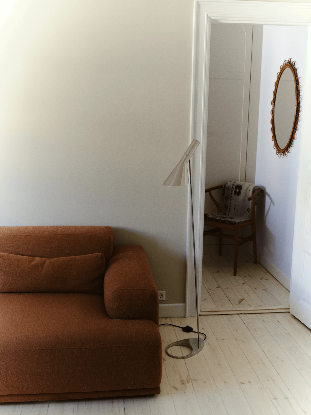 AJ Floor Lamp beside sofa creating focused reading light in living room, © 2025 Louis Poulsen.