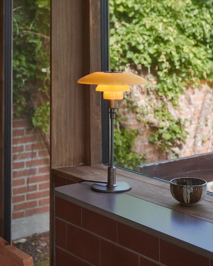PH 3/2 Table Lamp Fendi Casa on window sill with garden view, © 2025 Louis Poulsen.