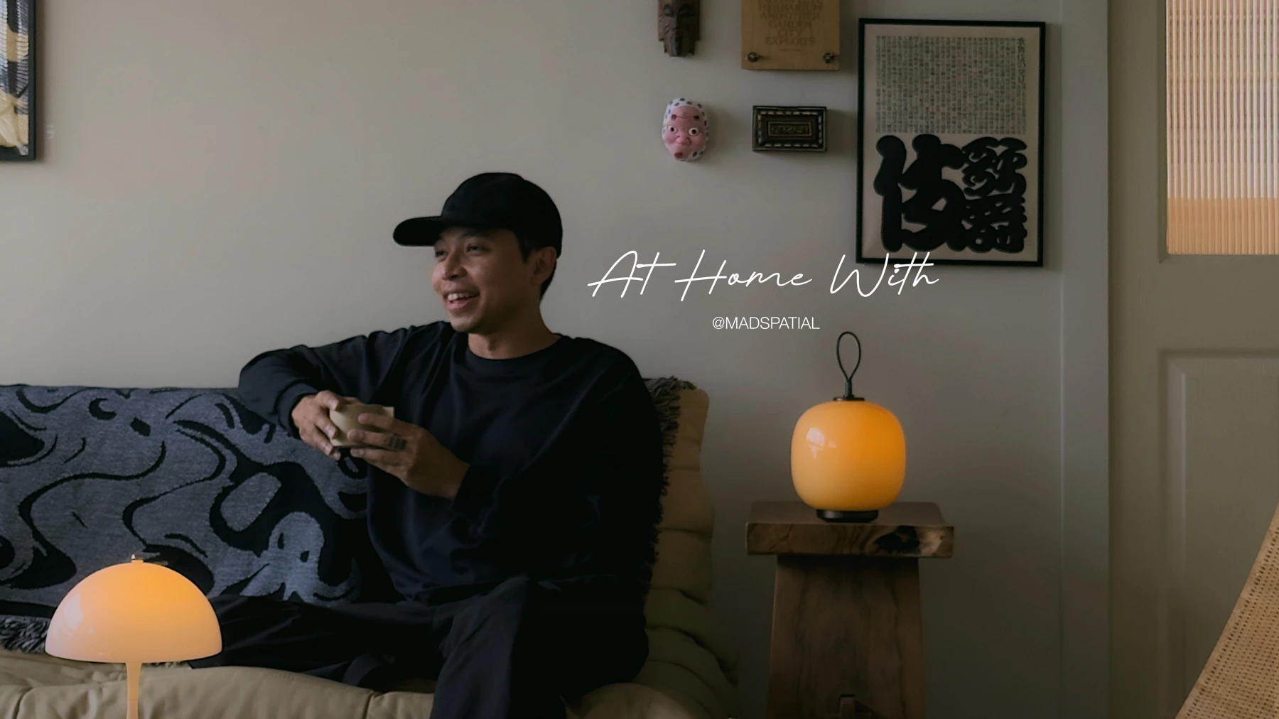 Adriano Tawin drinking coffee by a glowing Portable Table Lamp on a wooden table in a cozy living room, © 2025 Louis Poulsen.