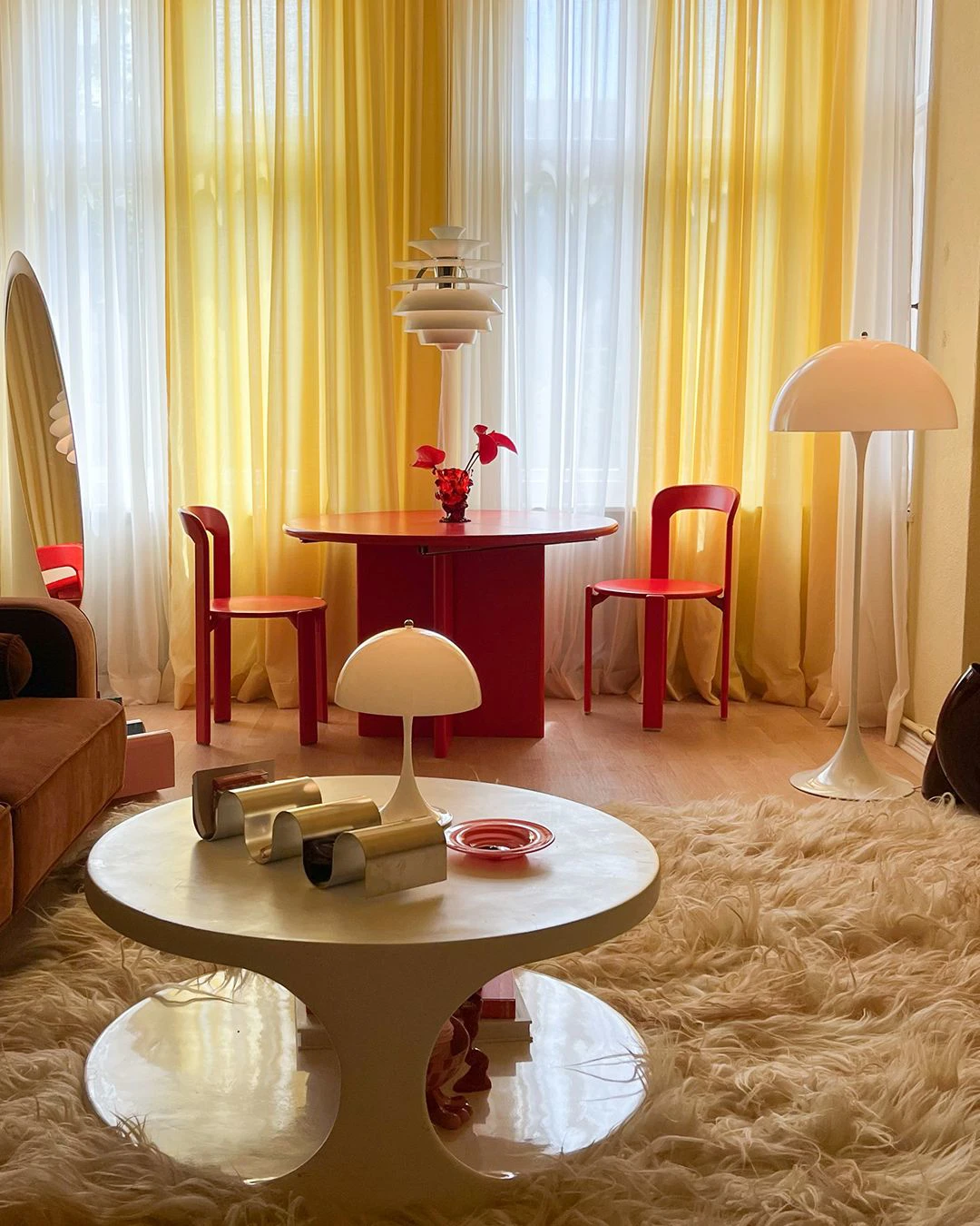 Living room with PH Snowball pendant and Panthella lamps complementing red and yellow decor, © 2025 Louis Poulsen.