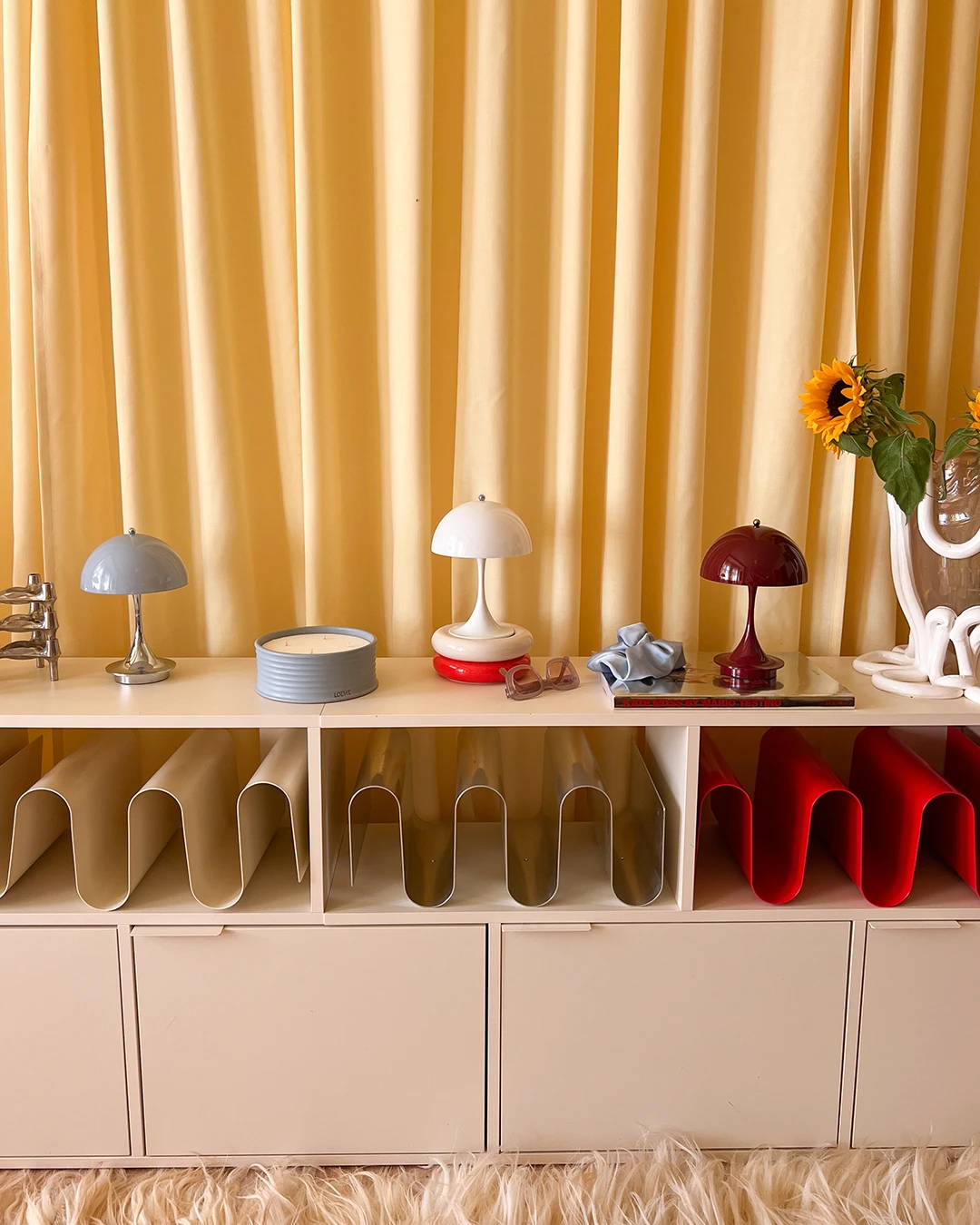 Three Panthella 160 Portable lamps in Chrome Blue Opal, White, and Burgundy on shelf, © 2025 Louis Poulsen.