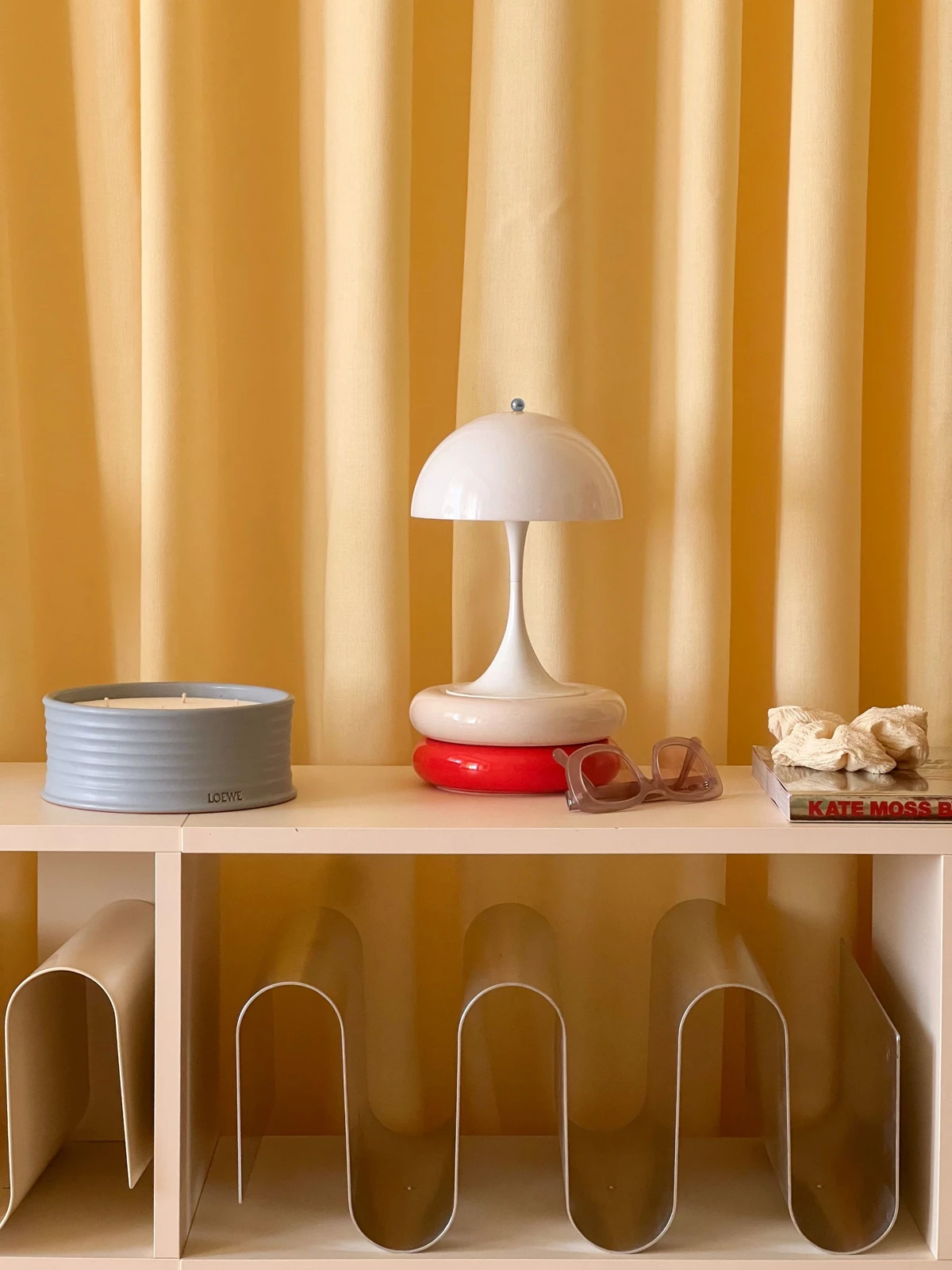 Panthella 160 Portable in White on shelf against yellow curtains, © 2025 Louis Poulsen.