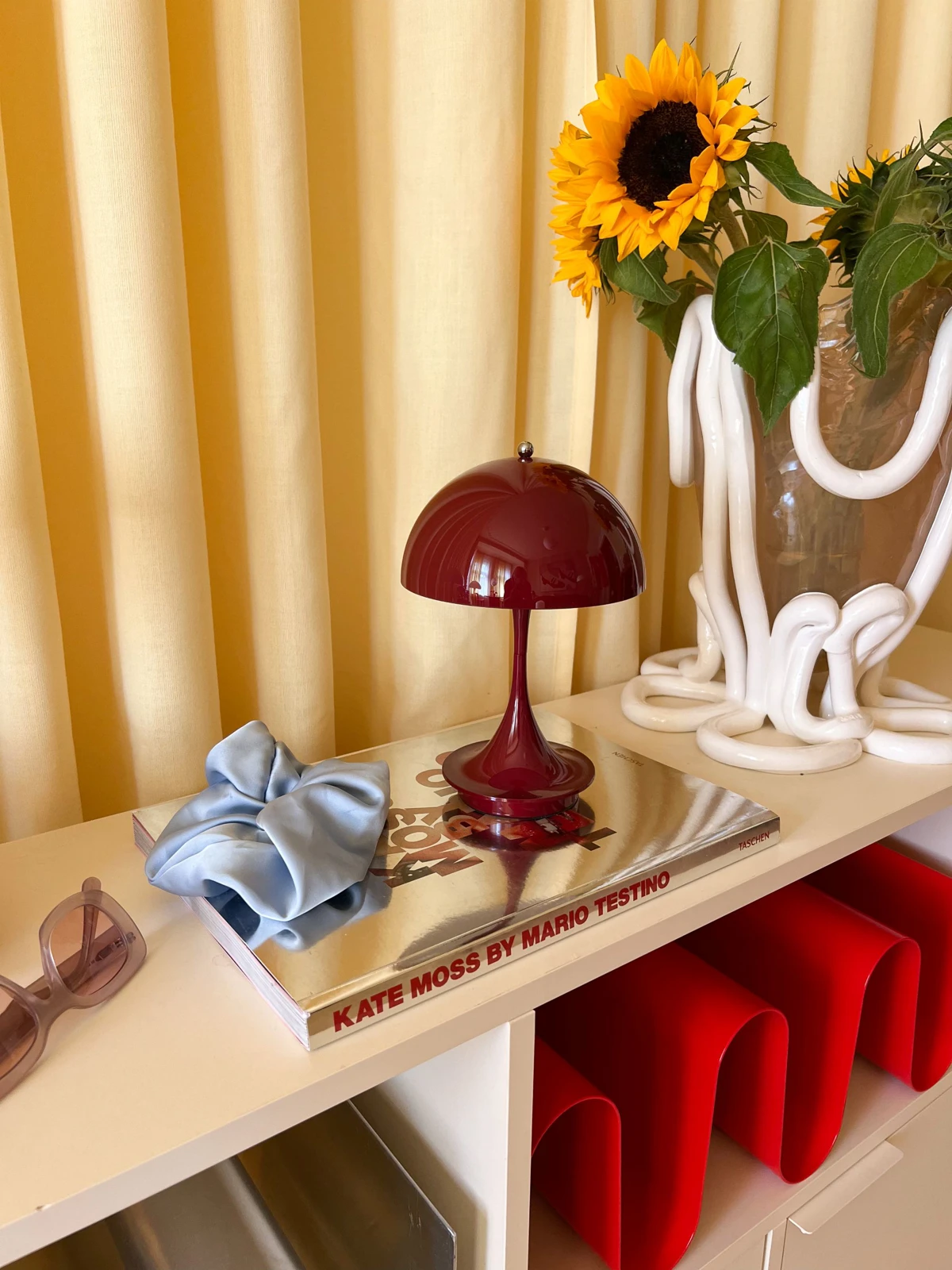 Panthella 160 Portable in Burgundy on shelf with sunflowers, © 2025 Louis Poulsen.