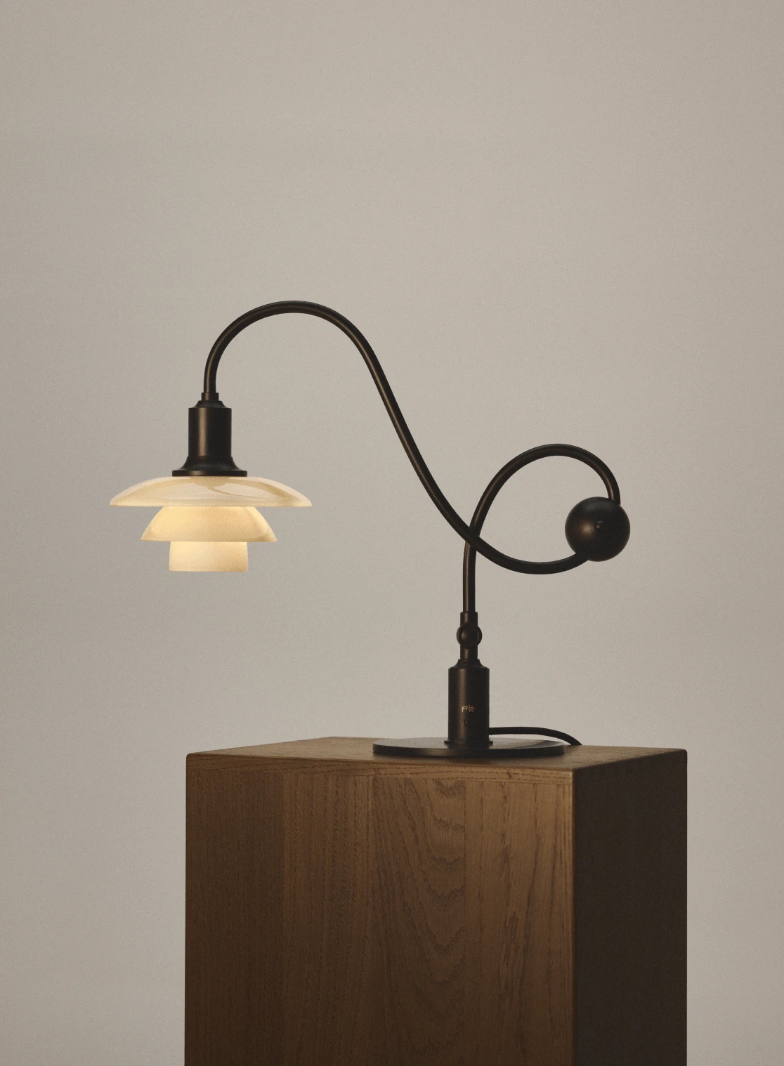PH 1/1 Piano Lamp이 목재 받침대 위에서 점등된 모습, © 2025 Louis Poulsen.