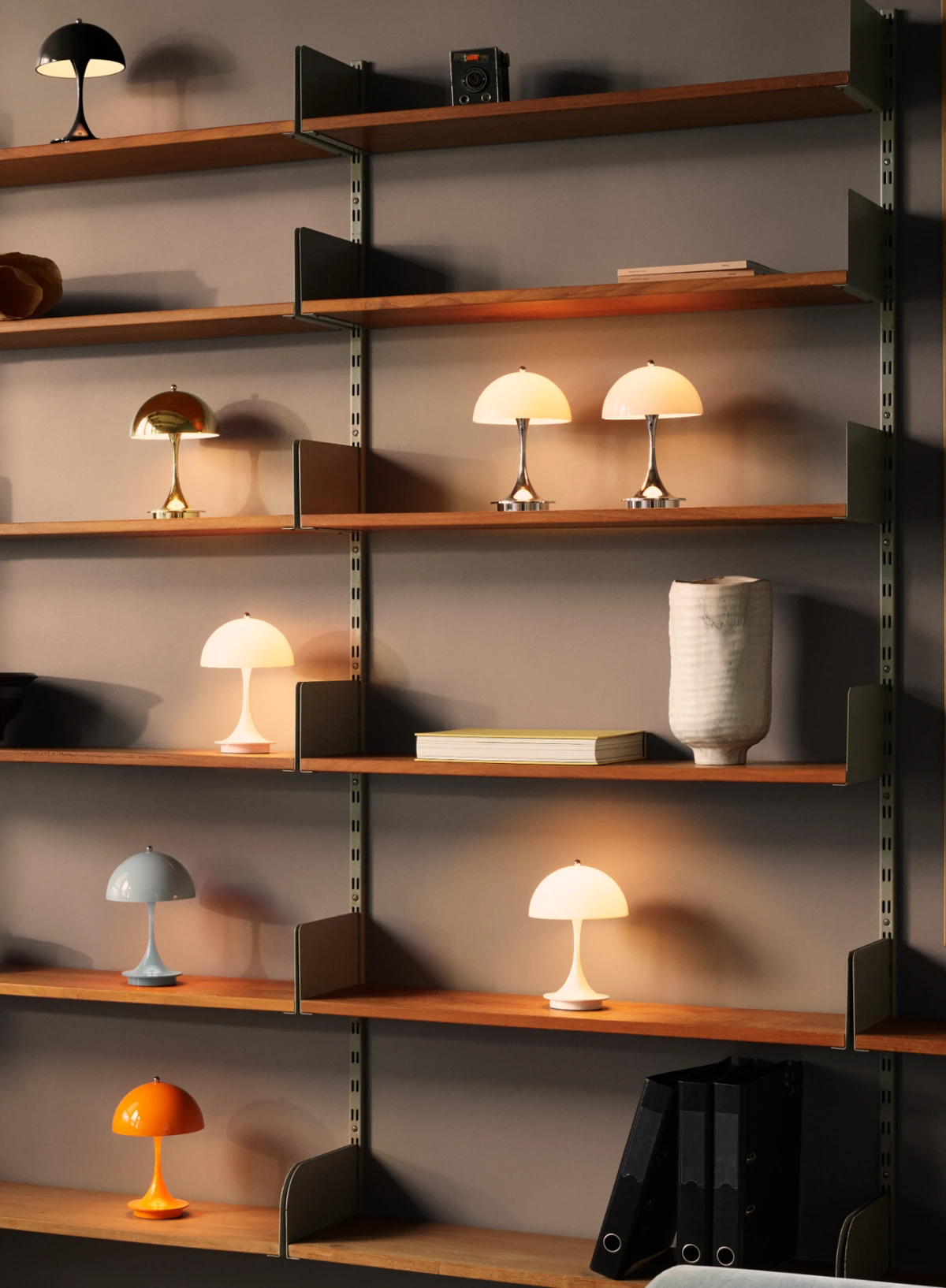 Panthella 250 Portable Lamp in verschiedenen Farben stehen auf Holzregalen neben Büchern und Keramik. © 2026 Louis Poulsen.