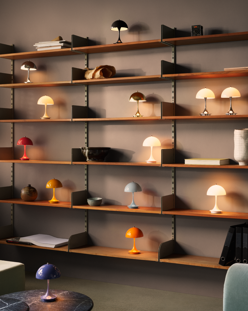 Panthella 160 Portable Lamps in a range of colours sit on shelves and a marble table in a warmly lit room. © 2026 Louis Poulsen.