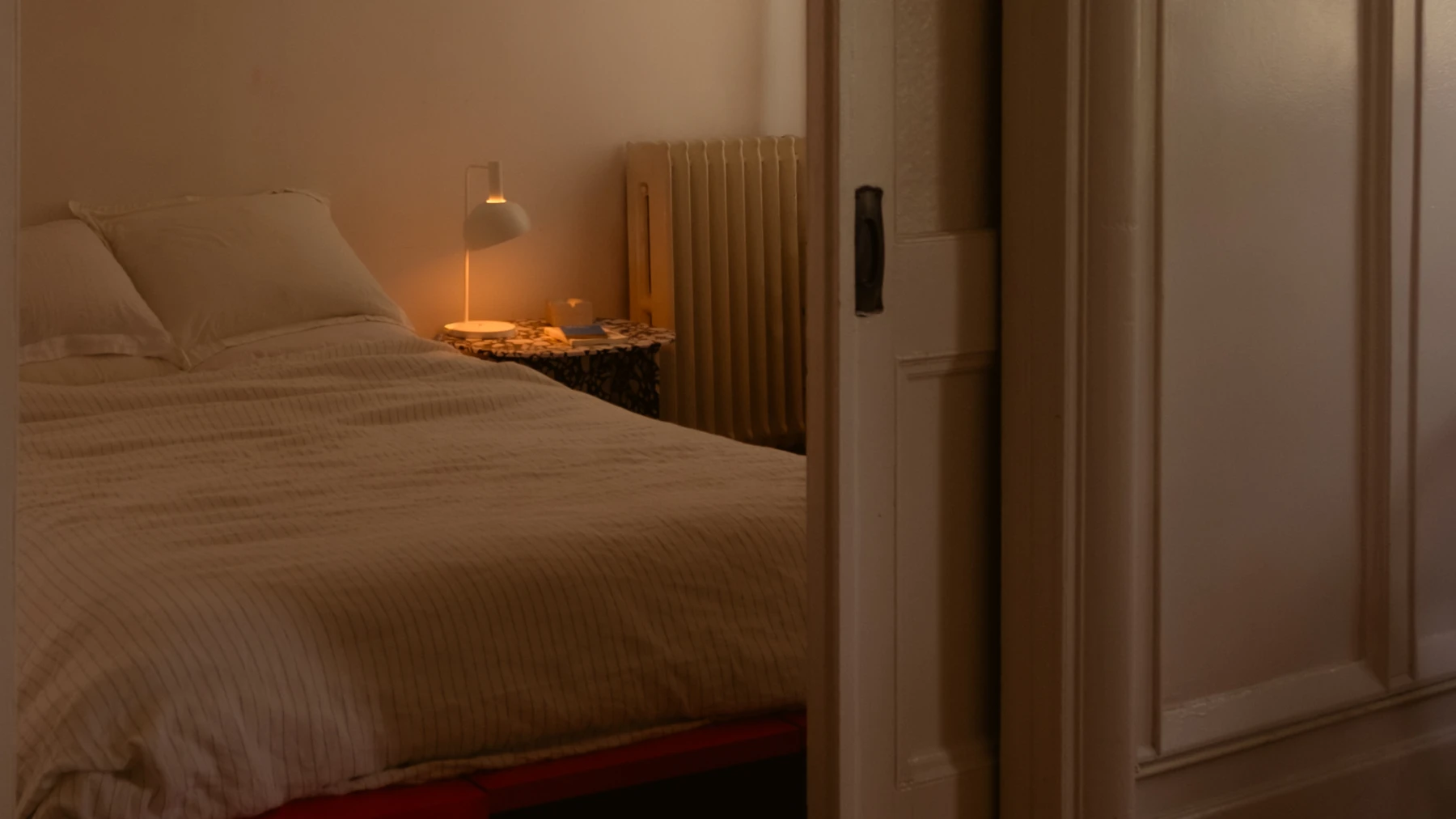 FJ Element Table Lamp in White illuminating bedside table in calm bedroom, © 2025 Louis Poulsen.