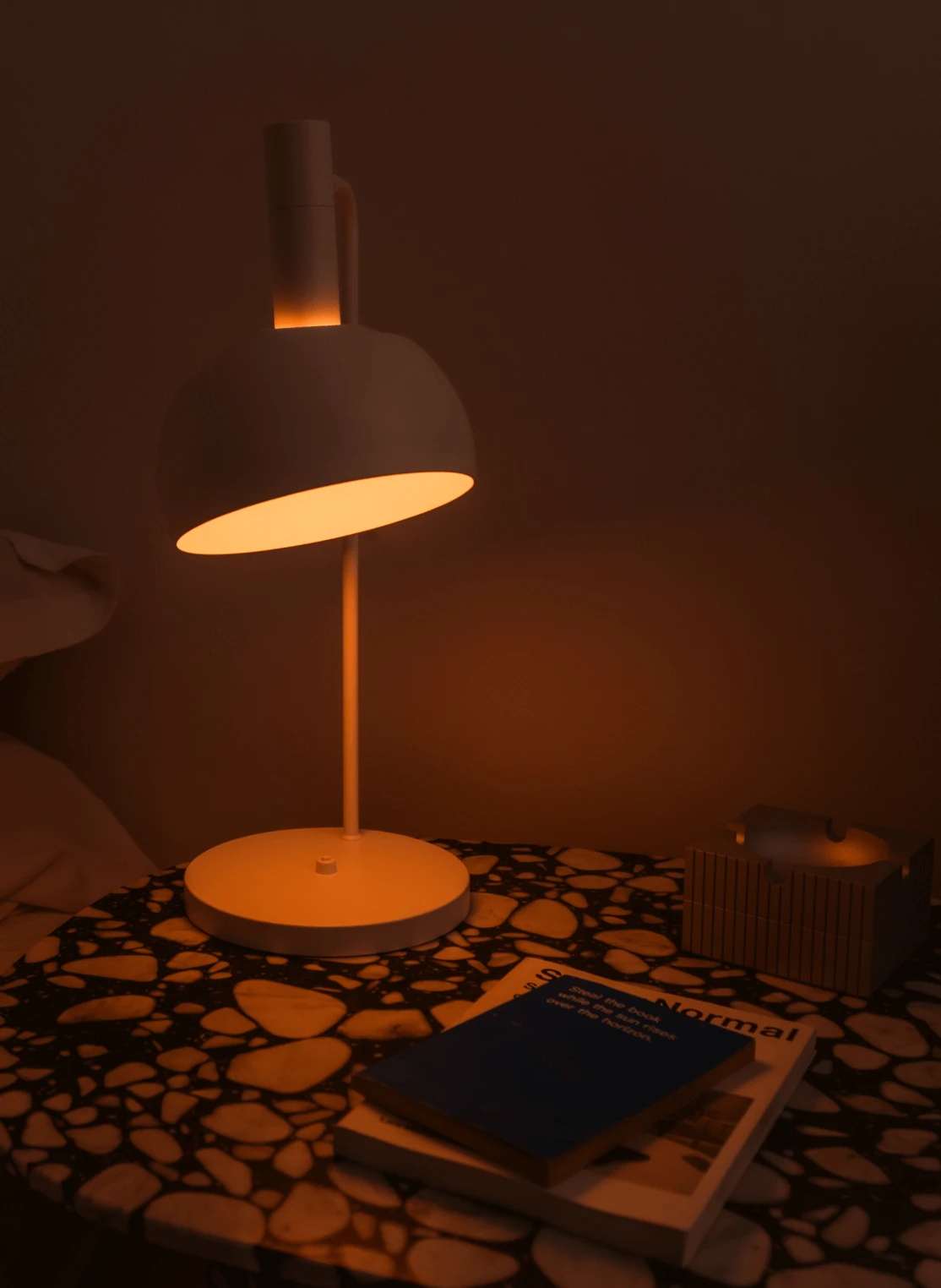 FJ Element Table Lamp in White glowing warmly on patterned bedside table, © 2025 Louis Poulsen.