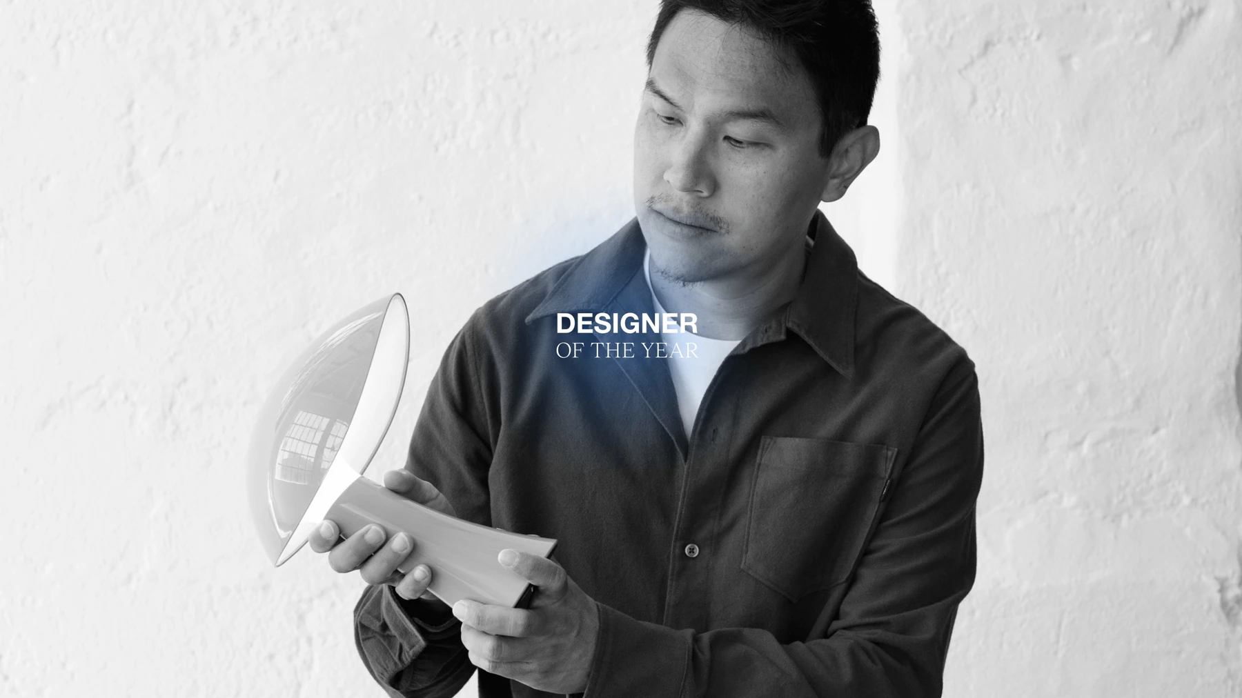 Designer holding a Rumee portable lamp, with a 'Designer of the Year' title, © 2025 Louis Poulsen.