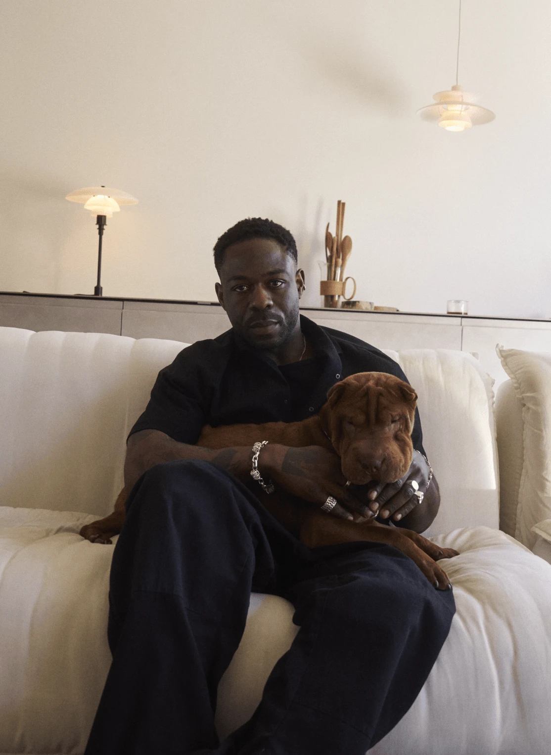 Jack Kabangu at home with his dog beneath illuminated PH lamps, © 2025 Louis Poulsen.
