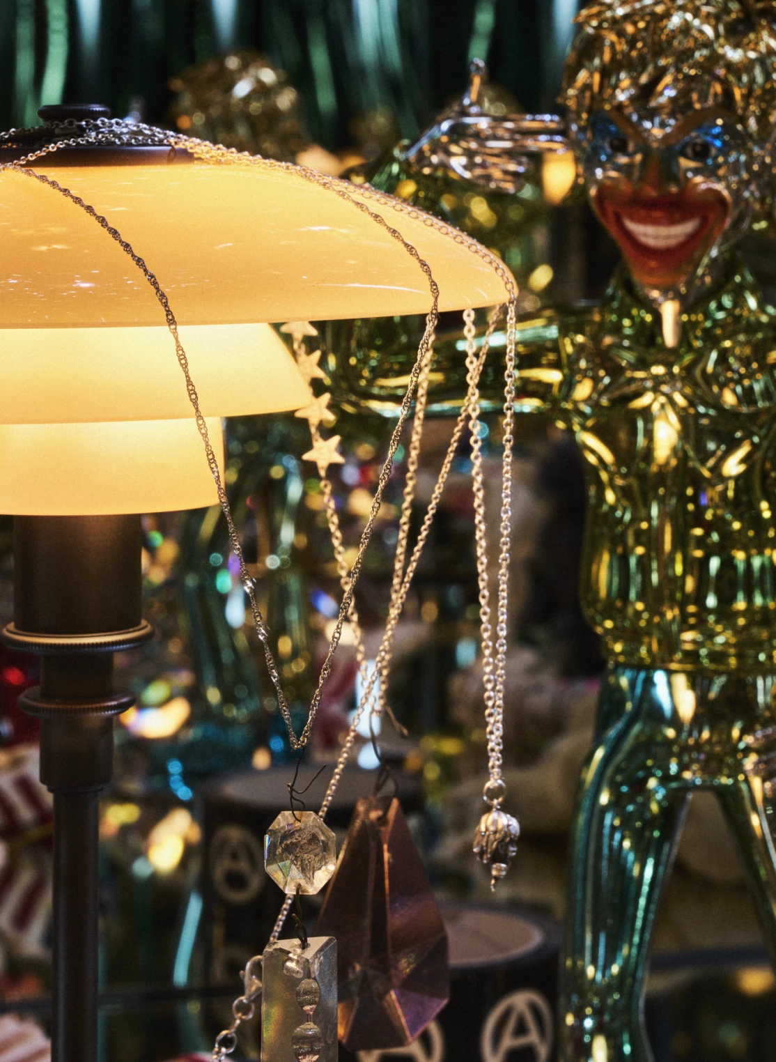 PH 2/1 Table Lamp with warm glowing shades amid draped jewellery and sparkling glass figures. © 2026 Louis Poulsen.