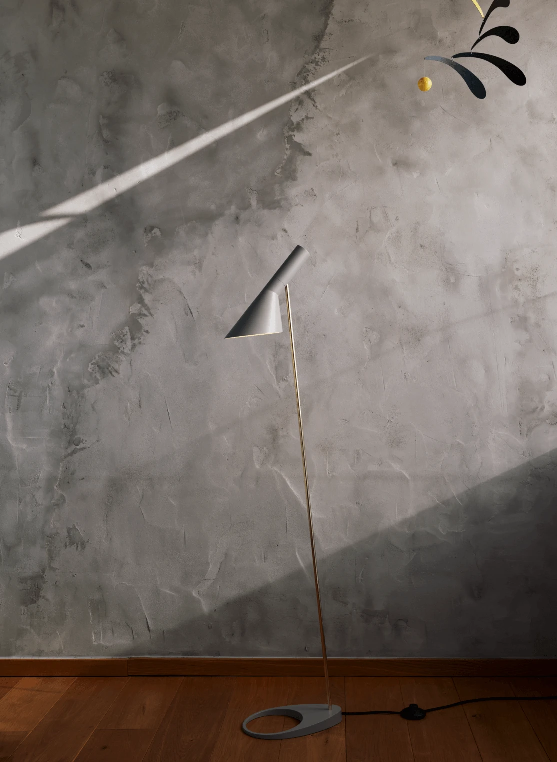 AJ Floor lamp against a textured wall with dramatic sunlight, © 2025 Louis Poulsen.