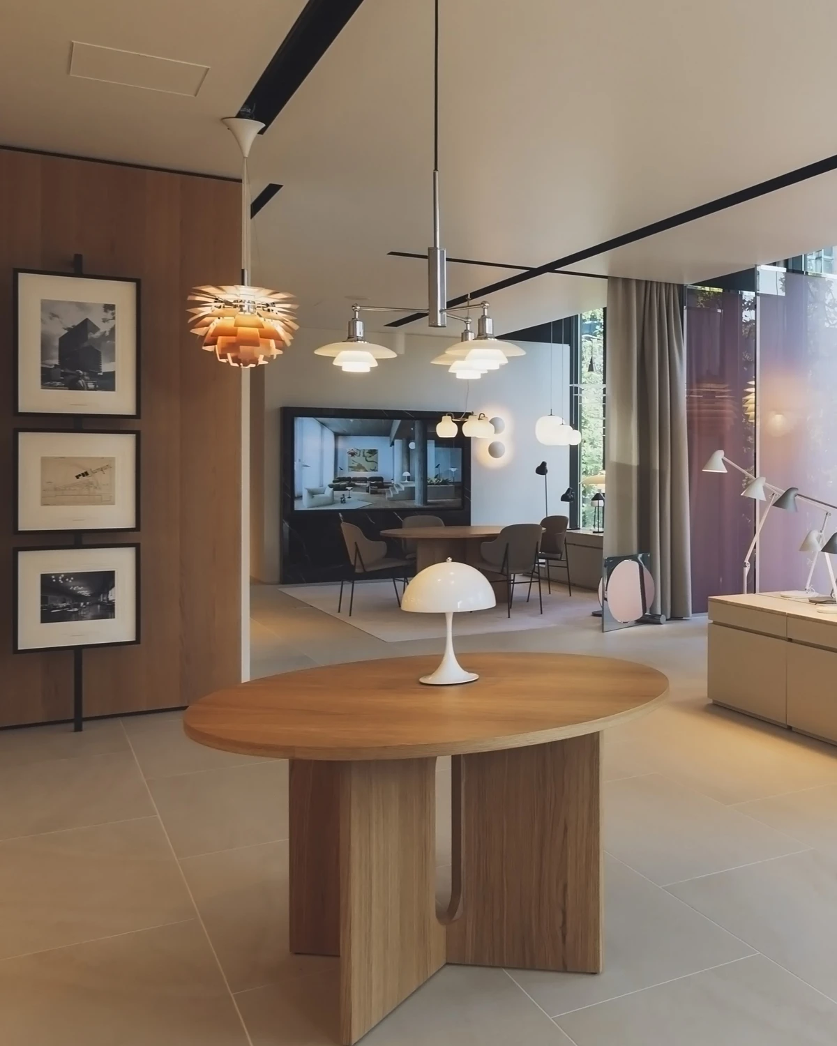 A white Panthella 250 Table Lamp stands on a round wooden table in Louis Poulsen’s Tokyo showroom, with PH Artichoke pendants. © 2026 Louis Poulsen.
