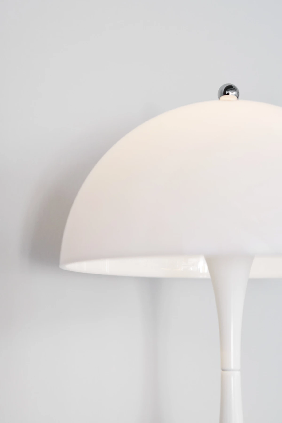 Close-up of a white Panthella 400 Table Lamp against a plain light grey background. © 2026 Louis Poulsen.