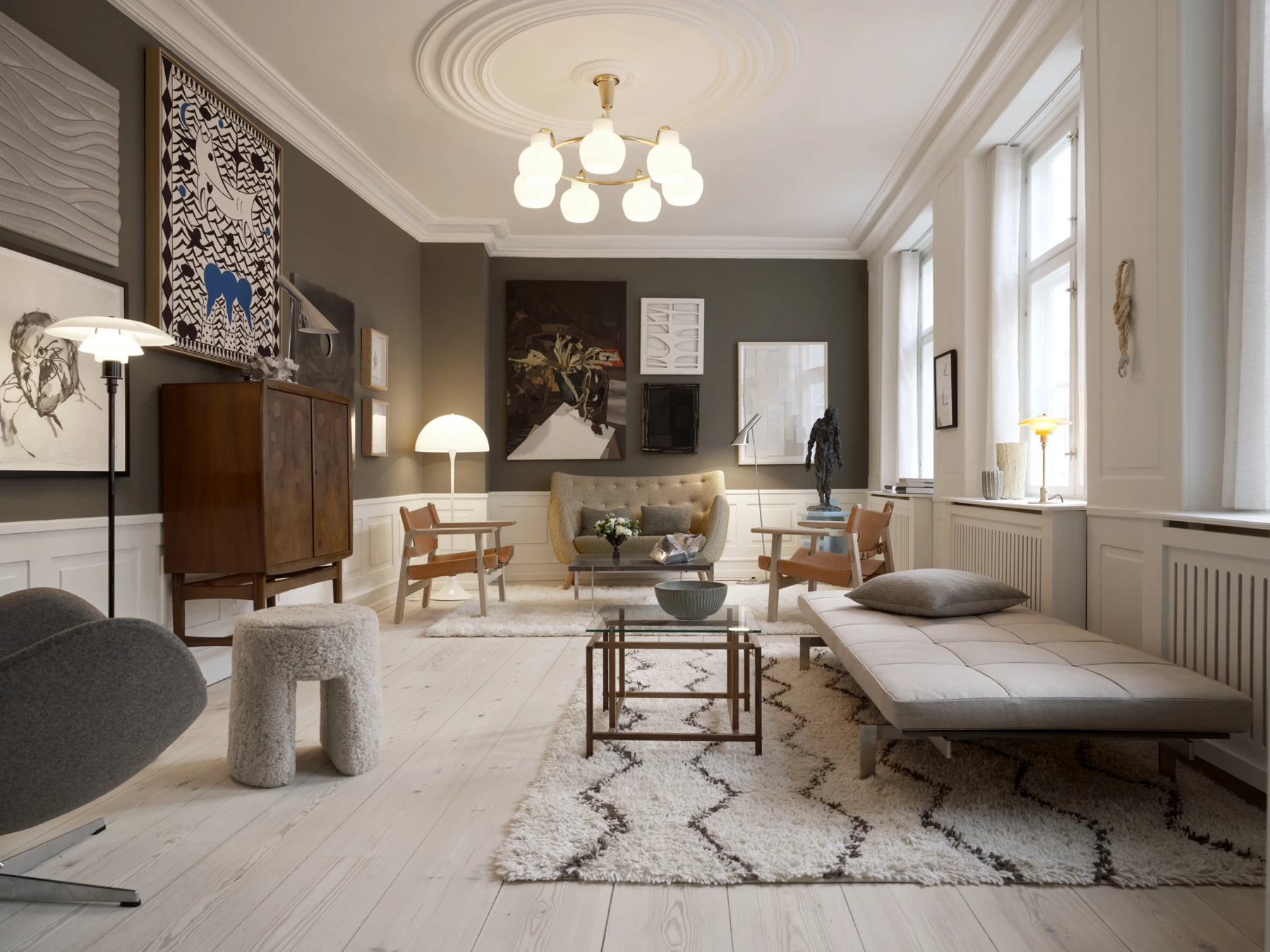 A VL Ring Crown 3-5-7 Pendant and PH 80 Floor Lamp light a modern living room with artwork and pale wood floors. © 2026 Louis Poulsen.