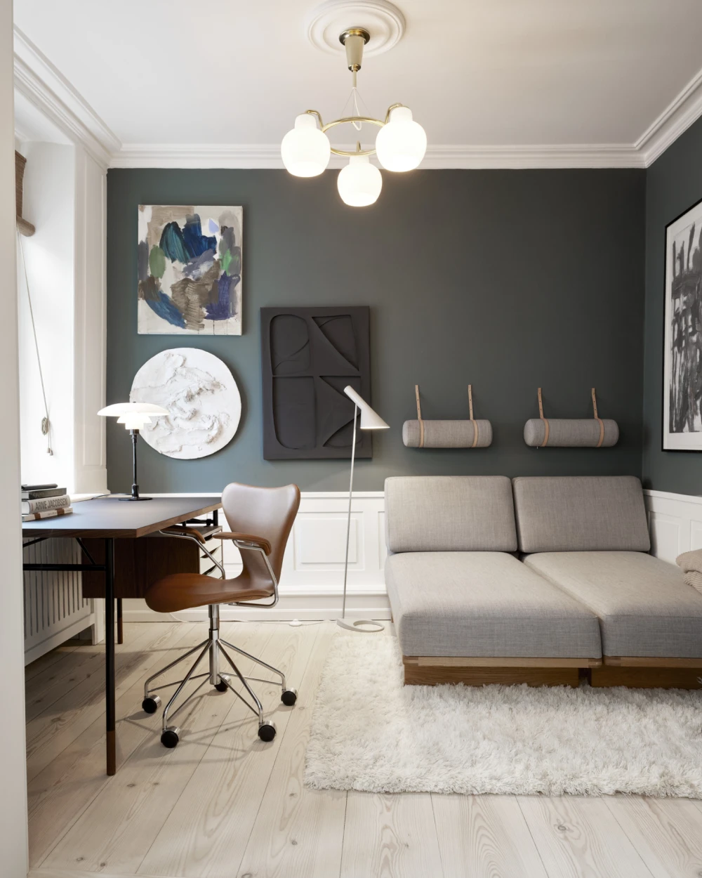 A VL Ring Crown 3-5-7 Pendant, PH 2/1 Table Lamp and AJ Floor Lamp illuminate a living room with a dark wall. © 2026 Louis Poulsen.