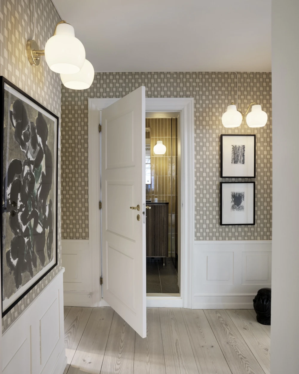 Two VL Ring Crown 2 Wall Lamps in opal glass and brass light a patterned hallway. © 2026 Louis Poulsen.