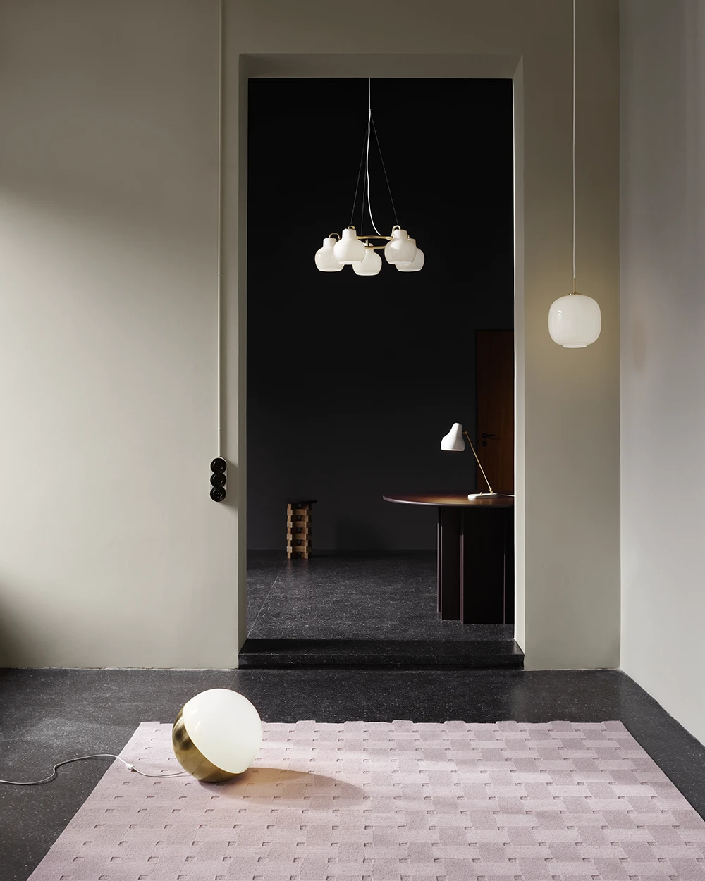 Een PH 2/2 Luna tafellamp met opaalglazen kap staat op een vloerkleed onder een VL Ring Crown 3-5-7 hanglamp. © 2026 Louis Poulsen.