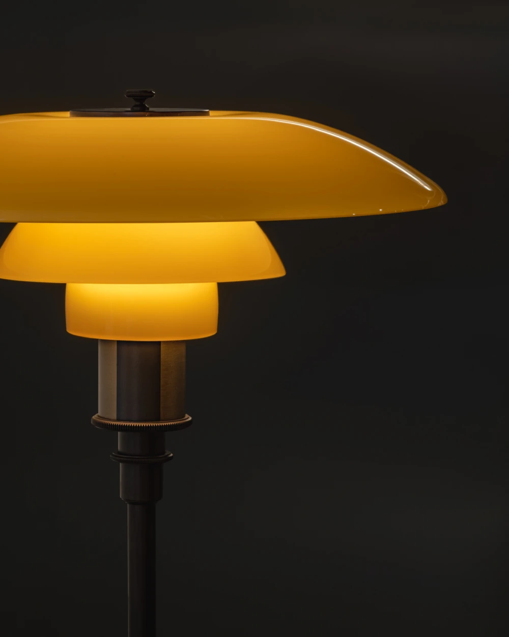 The PH 3½-2½ Metal Table Lamp glows in a warm golden finish against a dark background. © 2026 Louis Poulsen.