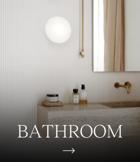 A VL Ring Crown 1 Wall Lamp glows above a bathroom vanity against pale, ribbed walls. © 2026 Louis Poulsen.