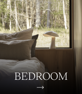 Bedroom with a white Panthella 250 Portable Lamp by the window, overlooking the forest. © 2026 Louis Poulsen.