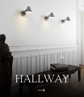 Three grey AJ Wall Lamps light a white hallway with panelled walls and a dark console table. © 2026 Louis Poulsen.
