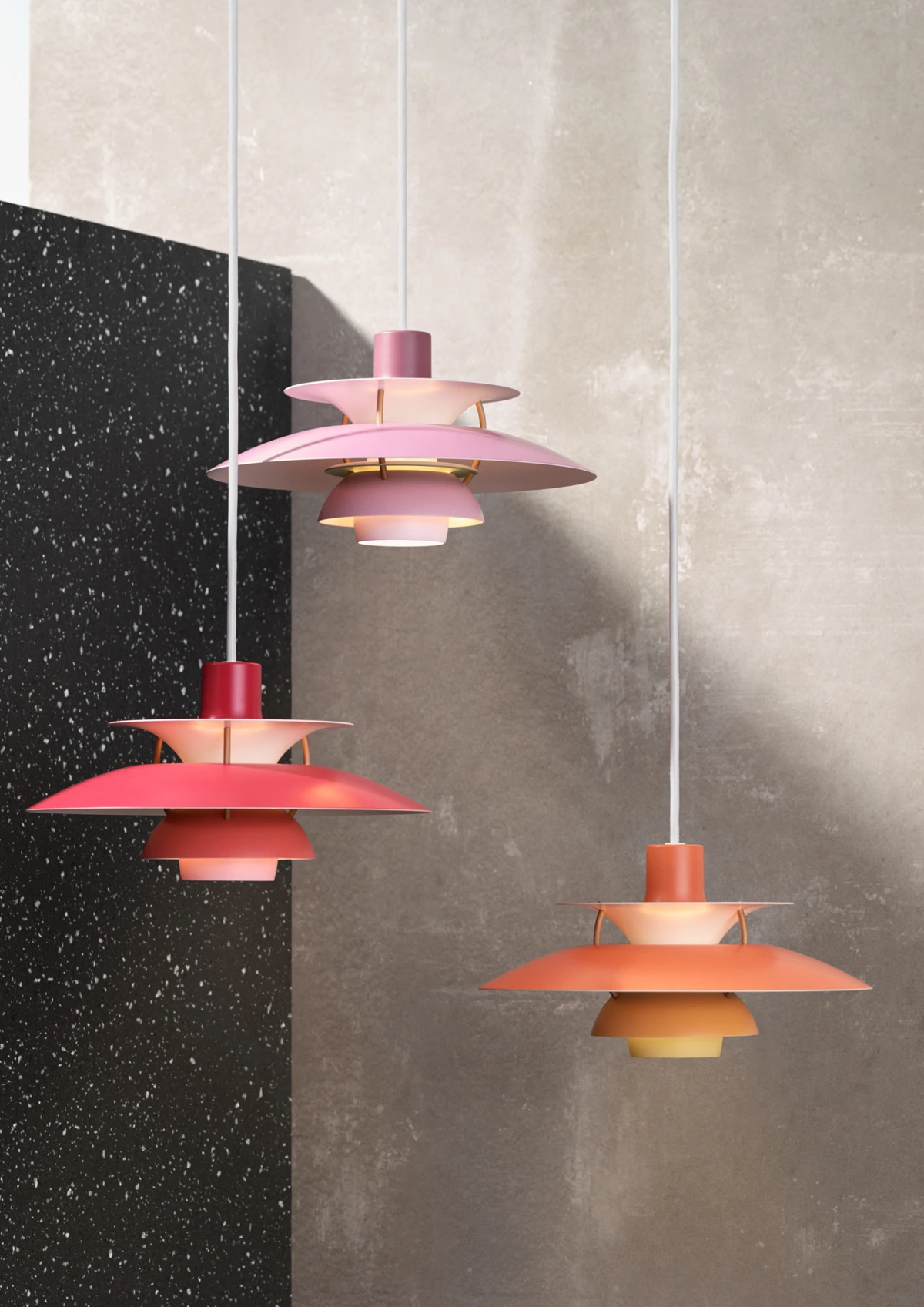 Three PH 5 pendants in pink, red and orange hang against a pale wall in a children’s room. © 2026 Louis Poulsen.