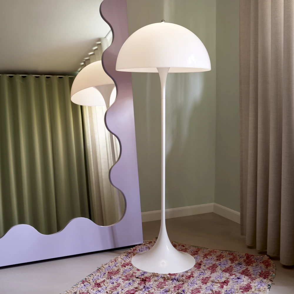 A white Panthella Floor Lamp stands on a colourful rug in a children’s room with curtains and a wavy mirror. © 2026 Louis Poulsen.