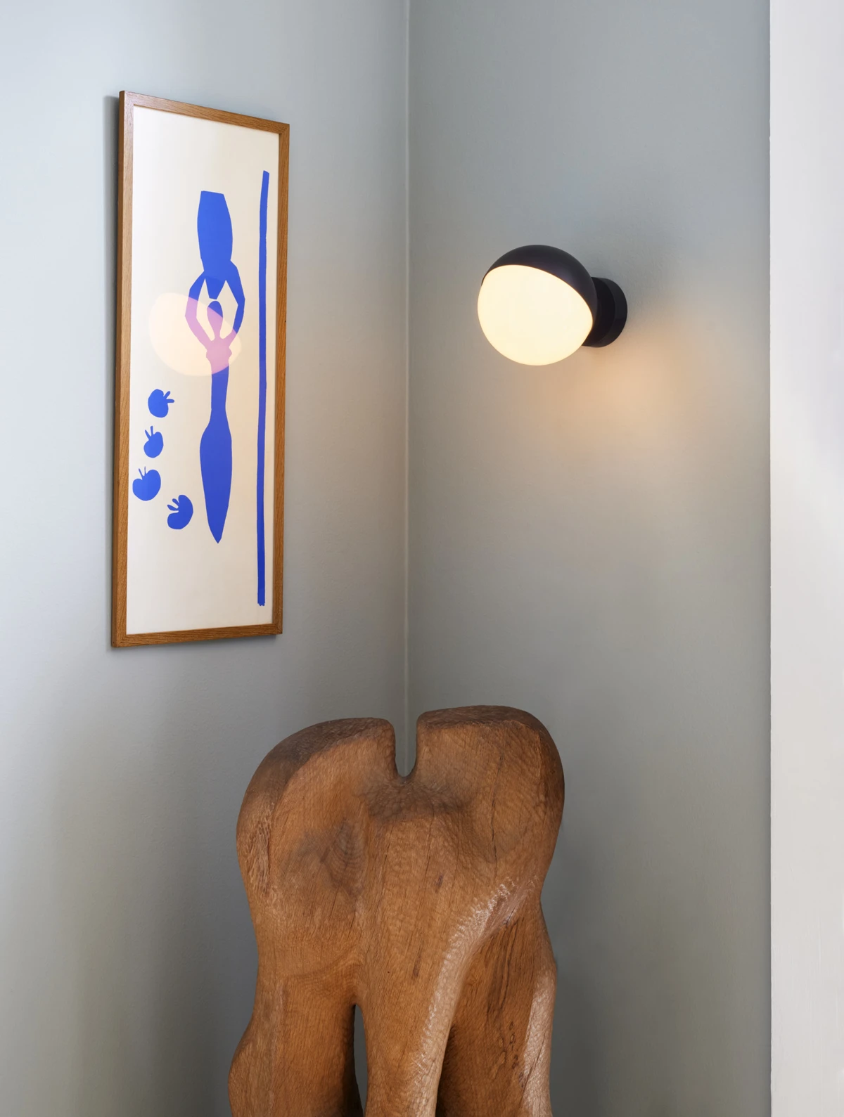Een zwarte VL Studio wandlamp met opaalglas verlicht een houten sculptuur in een kinderkamer. © 2026 Louis Poulsen.