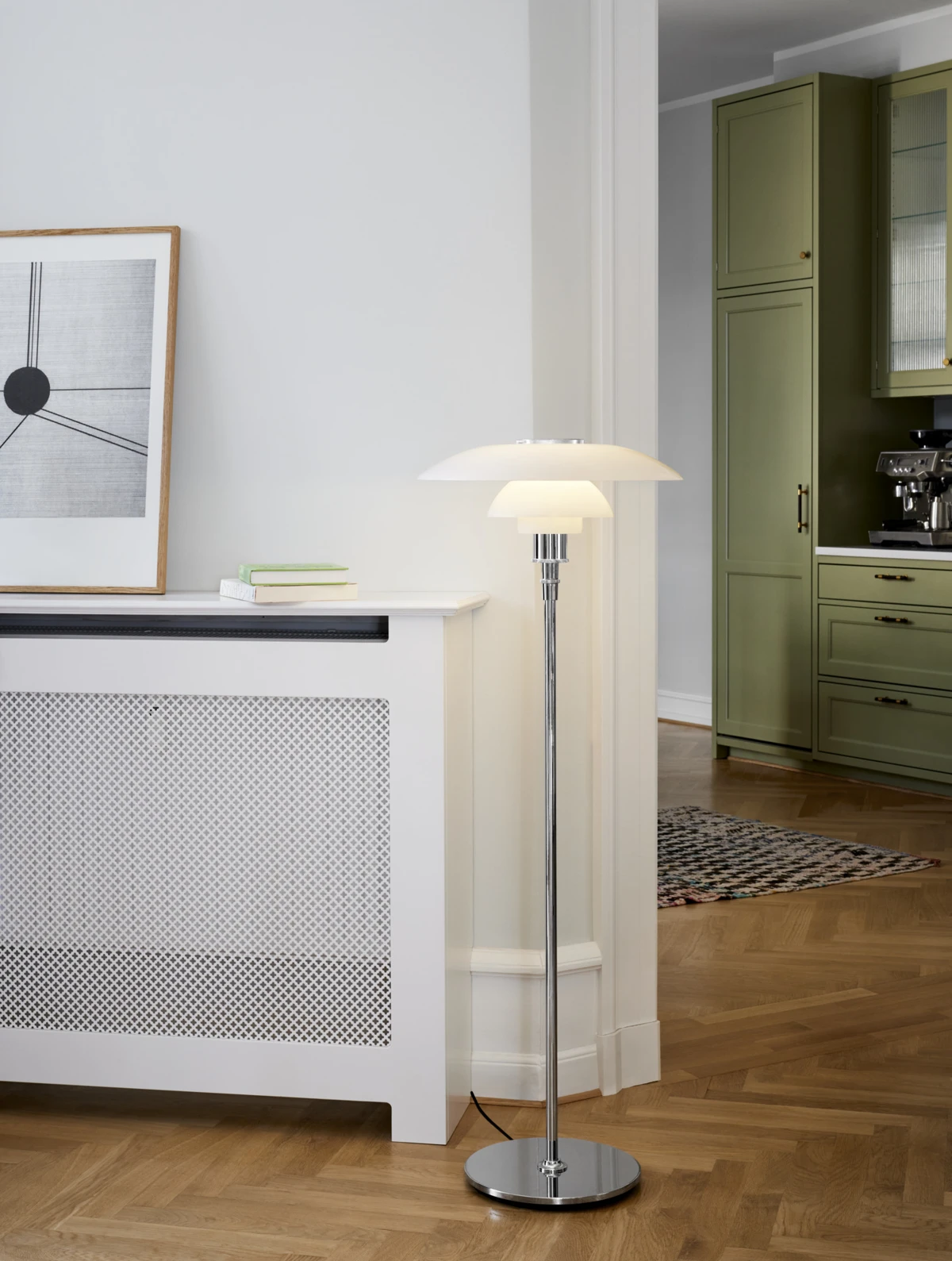 A PH 4½-3½ Floor Lamp in opal glass with a chrome stem stands beside a desk in a bright home office. © 2026 Louis Poulsen.