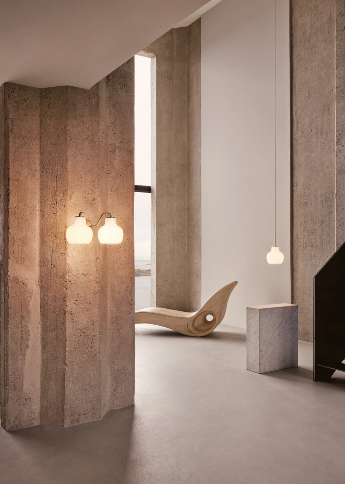A VL Ring Crown 2 Wall Lamp and VL Ring Crown 1 Pendant glow in a room with raw concrete walls. © 2026 Louis Poulsen.