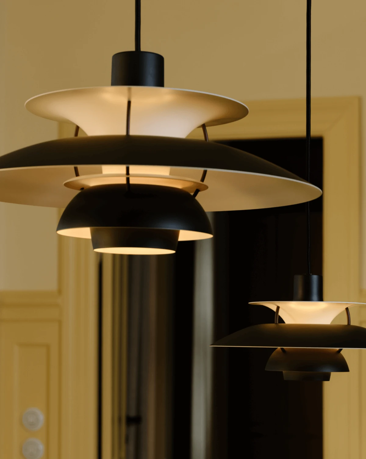 PH 5 and PH 5 Mini Black Edition pendants with warm light in interior setting, © 2025 Louis Poulsen.