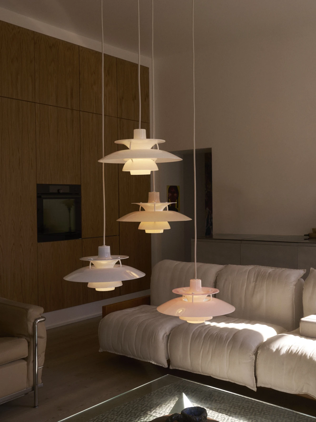 PH 5 Opal hanglampen in nieuwe kleuren boven een bank in warme woonkamer, © 2025 Louis Poulsen.