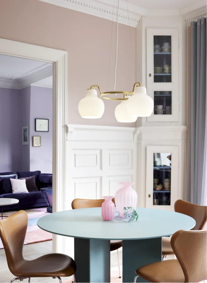 A VL Ring Crown 3-5-7 Pendant with white glass shades above a round dining table in a bright room. © 2026 Louis Poulsen.