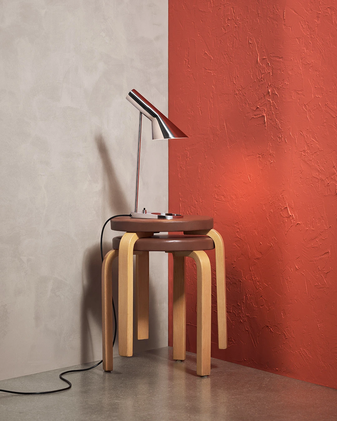 AJ Mini Table lamp in stainless steel on a wooden table, featuring classic design, © 2025 Louis Poulsen.
