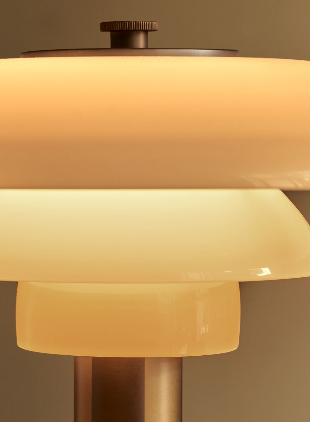 Close-up of the PH 2/1 Aged Brass Table Lamp, with glowing opal glass shades and brass details. © 2026 Louis Poulsen.