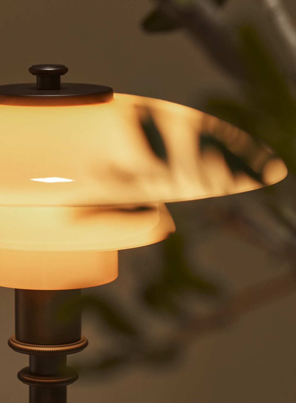 Nærbillede af PH 2/1 Dusty Terracotta bordlampe med varmt lys gennem glasskærmene. © 2026 Louis Poulsen.