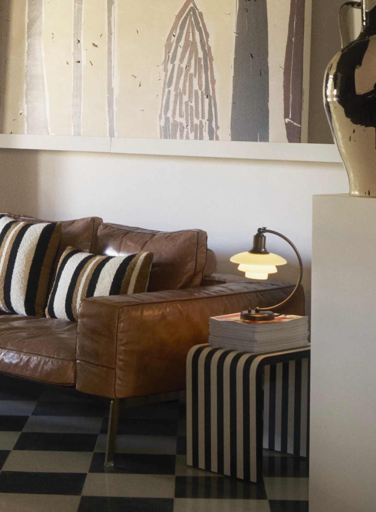 PH 2/2 Luna table lamp in aged brass on a striped side table, set in a cozy living space, © 2025 Louis Poulsen.