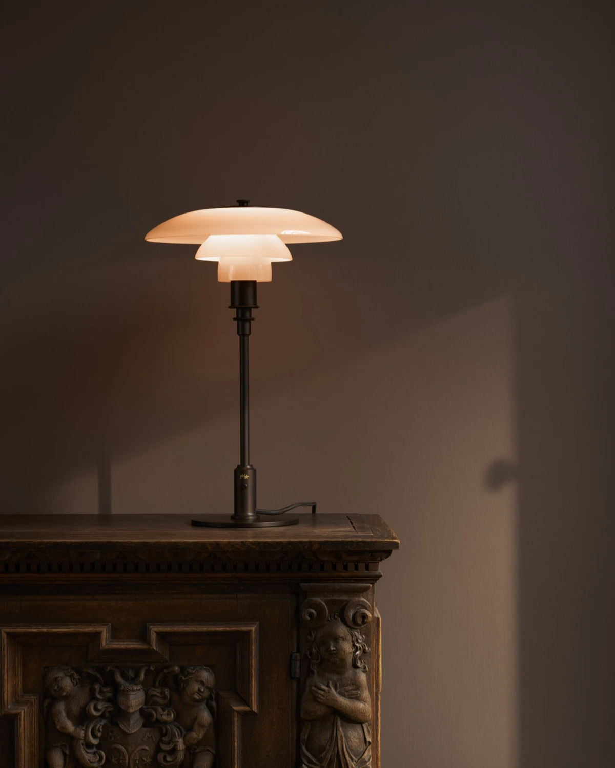 PH 3/2 Table Lamp terracotta on ornate wooden cabinet, softly lit room, © 2025 Louis Poulsen.