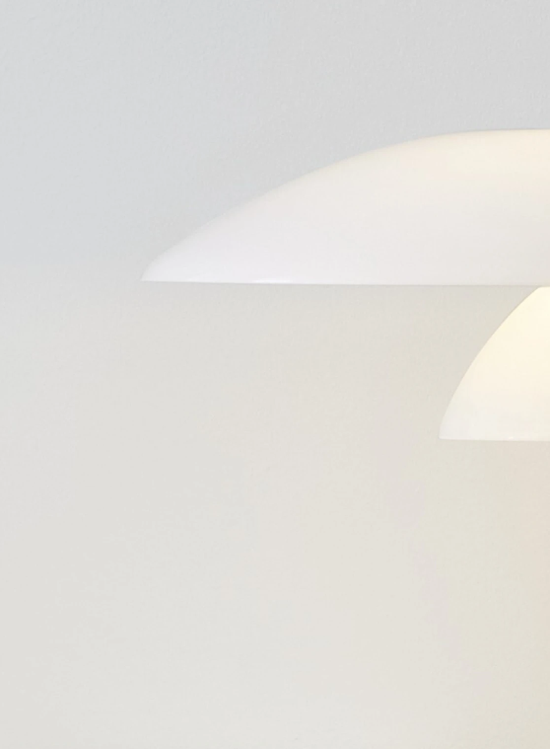 The white-glass PH 4/3 Table Lamp glows in close-up against a light, neutral background. © 2026 Louis Poulsen.